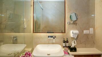 A bathroom with a large mirror, two sinks, a hairdryer, and a towel rack.