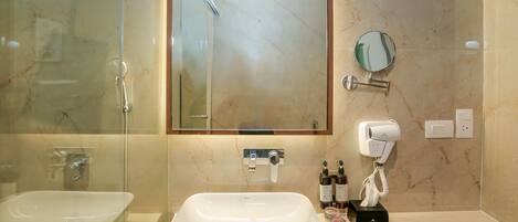 A bathroom with a large mirror, two sinks, a hairdryer, and a towel rack.