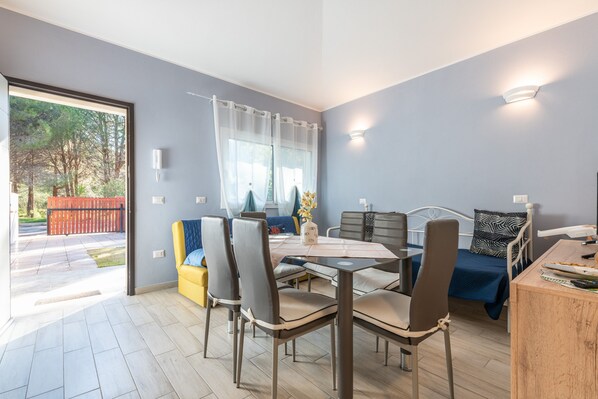 A modern dining area with a table, chairs, and a sofa.