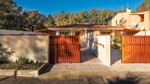 A gated entrance to a building with a tiled roof, a paved pathway, and a garden area. - Vacation Home "Ibiscus Rosa 1" with Mountain View, Terrace & A/C (Geremeas)