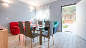 Uma sala de jantar com mesa, cadeiras e um sofá vermelho.