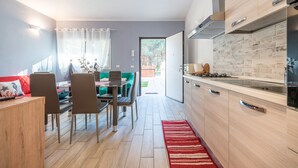 Uma cozinha moderna com fogão embutido, área de jantar com mesa e cadeiras, e vista para a sala de estar adjacente.