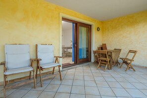 Une pièce comprenant deux chaises en bois, une petite table et une porte-fenêtre coulissante donnant sur une autre pièce.