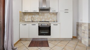 A compact kitchen with white cabinets, a gas stove, an oven, and a tiled backsplash.