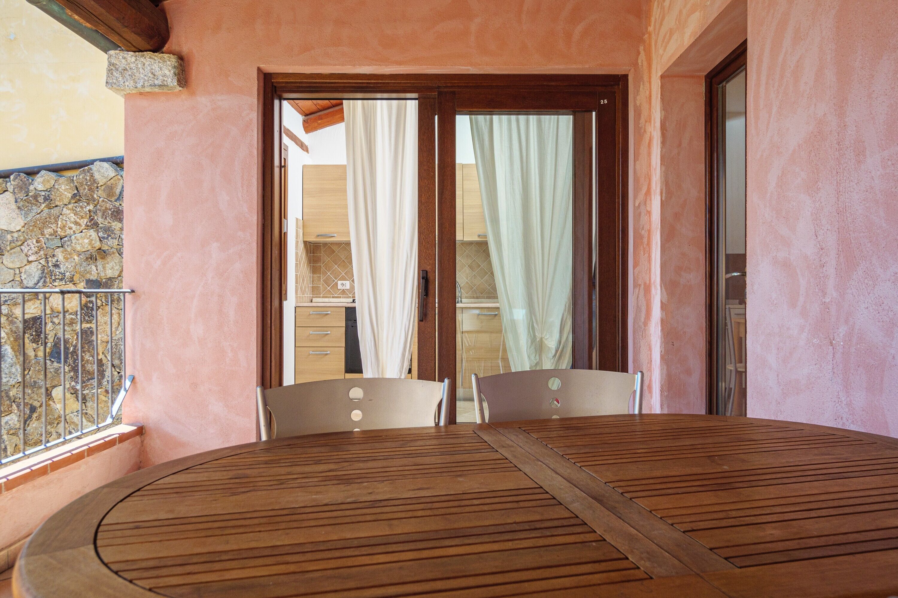 Ein Holztisch und Stühle auf einem Balkon mit einer Steinmauer und einer Holztür.