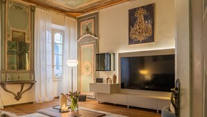 A modern living room with a large flat-screen TV, a fireplace, a chandelier, and a large mirror. - Rovelli 41 in Como With 2 Bedrooms and 3 Bathrooms (Como)
