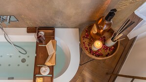 A bathroom with a bathtub, a wooden tray with books and a candle, and a round table with a bottle, candles, and reed diffusers. - Rovelli 41 in Como With 2 Bedrooms and 3 Bathrooms (Como)