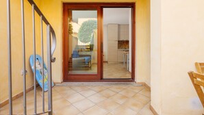 Un pasillo con piso de baldosas, una puerta de madera que da a una cocina y una reja metálica.