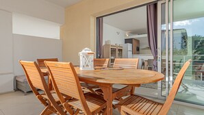 A wooden dining table with chairs, a lantern, and a view through a glass door to an outdoor area.