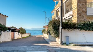 A coastal street with a clear view of the sea and mountains in the distance.