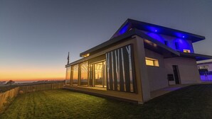 Ein modernes Haus mit großen Glasfenstern, einem Flachdach und einer Fahnenstange.