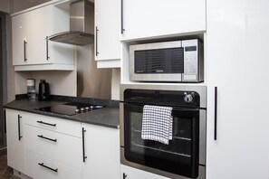 A modern kitchen with white cabinetry, a built-in microwave, and an oven.