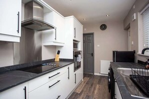 Une cuisine moderne avec des meubles blancs, un plan de travail noir et des appareils en acier inoxydable.