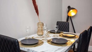 A dining table set with black plates, gold placemats, and clear wine glasses. - Modern Interior Spacious  Four Bedroom Apartment (South Shields)