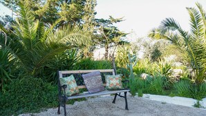 A bench with patterned cushions in a garden setting.