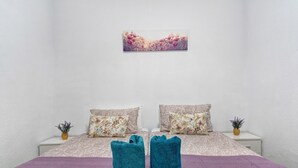 A bedroom with a bed, two pillows, a purple blanket, and two towels. - Holiday Apartment "Un Descanso 1" in City Center with Wi-Fi (San Fernando)