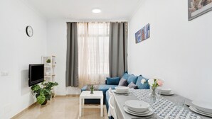 A modern living room with a sofa, dining table set, a TV, and a potted plant. - Holiday Apartment "Un Descanso 1" in City Center with Wi-Fi (San Fernando)