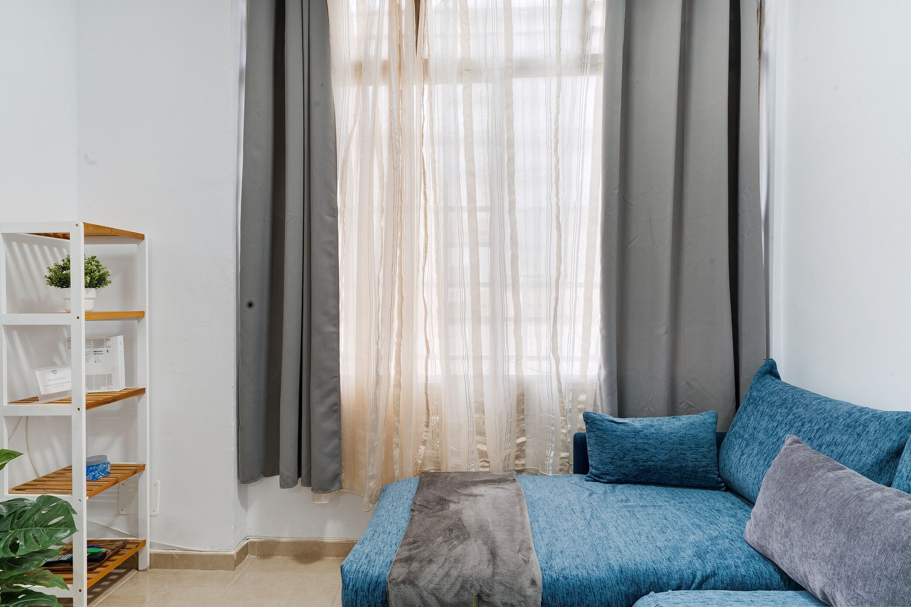 Ein Schlafzimmer mit einem Bett, einem Bücherregal und einem Fenster mit Vorhängen.