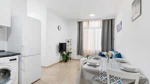 A modern kitchen with a washing machine, a dining area with a table set for four, and a living area with a TV and plants. - Holiday Apartment "Un Descanso 1" in City Center with Wi-Fi (San Fernando)