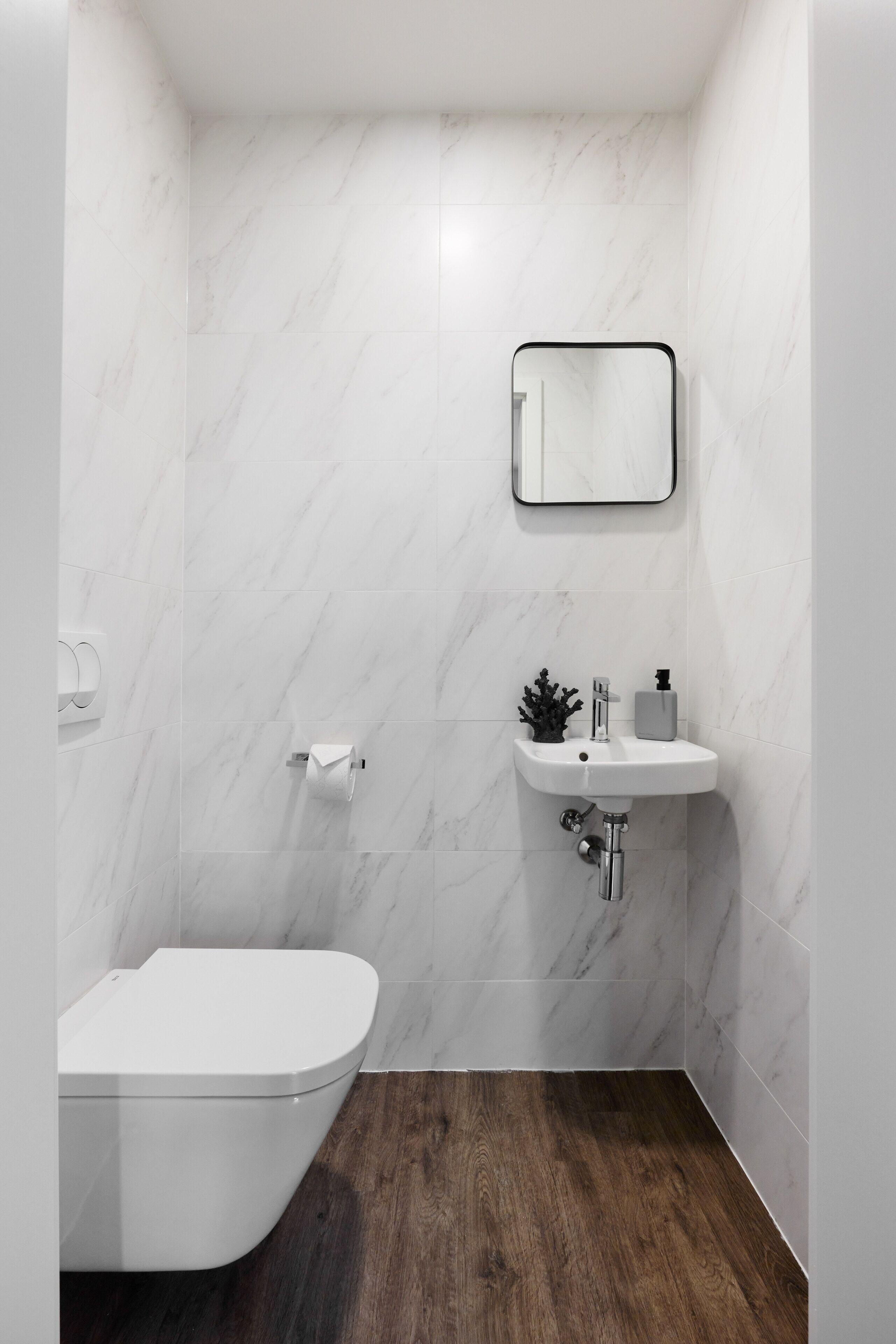 A bathroom with a toilet, a sink, and a mirror.
