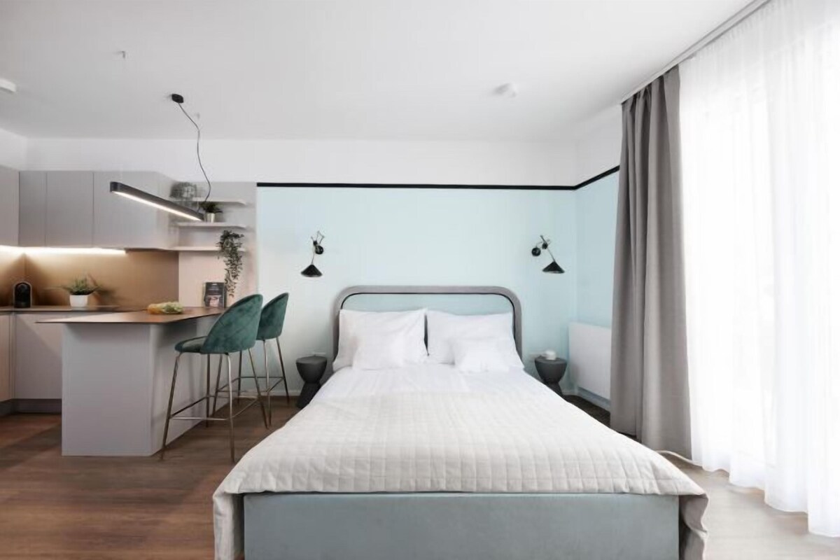 A modern bedroom with a bed, a desk, and chairs.