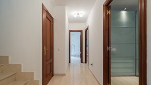Un pasillo con puertas de madera, una escalera y un portallama leading to una habitación.