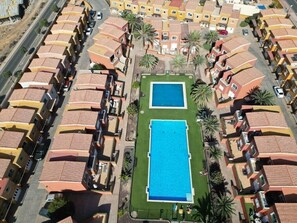 Vue aérienne d’un quartier résidentiel avec deux piscines entourées d’immeubles d’appartements.