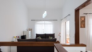 Una sala de estar moderna con un sofá, una mesa de centro de madera, un armario blanco y una lámpara colgante.