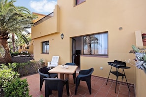 Un patio con una mesa y sillas, una pequeña silla negra, una ventana y una puerta.