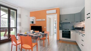 Eine moderne Küche mit Essbereich, ausgestattet mit einem Tisch, Stühlen, einem Fernseher und einem großen Fenster.