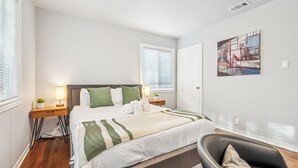 Une chambre à coucher moderne avec un lit, des tables de chevet, une chaise et un tableau au mur.