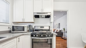 Une cuisine moderne avec des meubles blancs, un four à micro-ondes, une cuisinière et un évier.