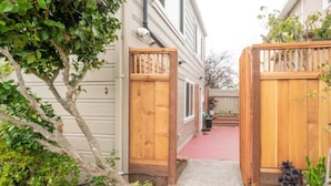 A narrow pathway leading to a gated entrance with a red-tiled patio area. - Luxo Stays |Modern Studio| Near SFO, Westlake BART (Daly City)