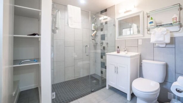 Une salle de bain moderne avec une douche à parois de verre, un lavabo blanc et des toilettes.