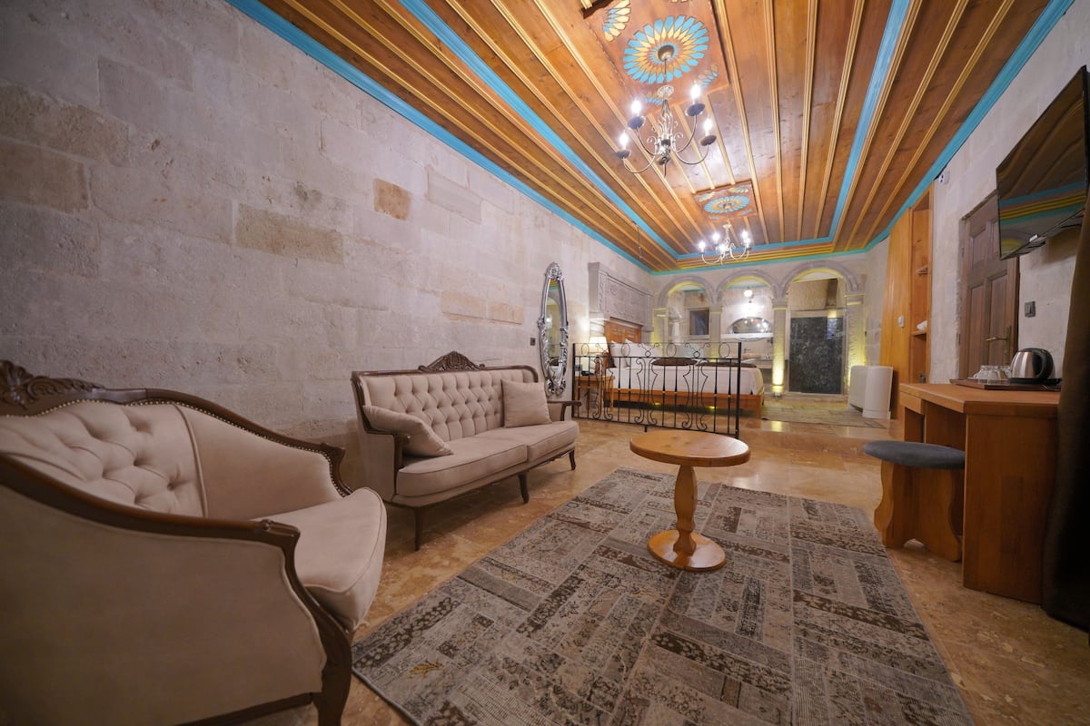 A spacious living room with a fireplace, a sofa, a coffee table, and a kitchen area in the background.