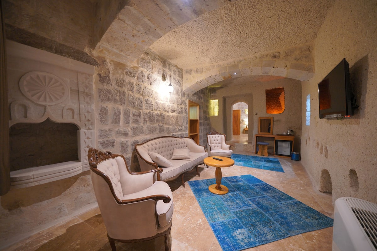 A stone-walled room with a fireplace, a sofa, a chair, and a small table.