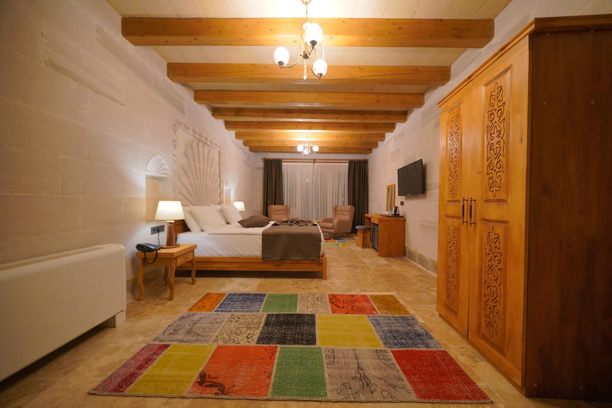 A bedroom with a bed, bedside table, lamp, and a colorful rug.