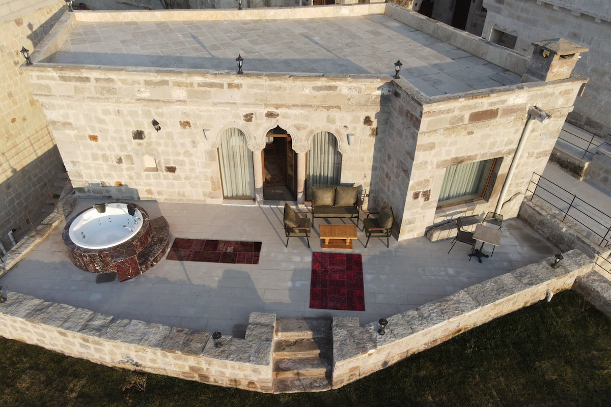 An aerial view of a stone building with a rooftop terrace, a hot tub, and outdoor seating.