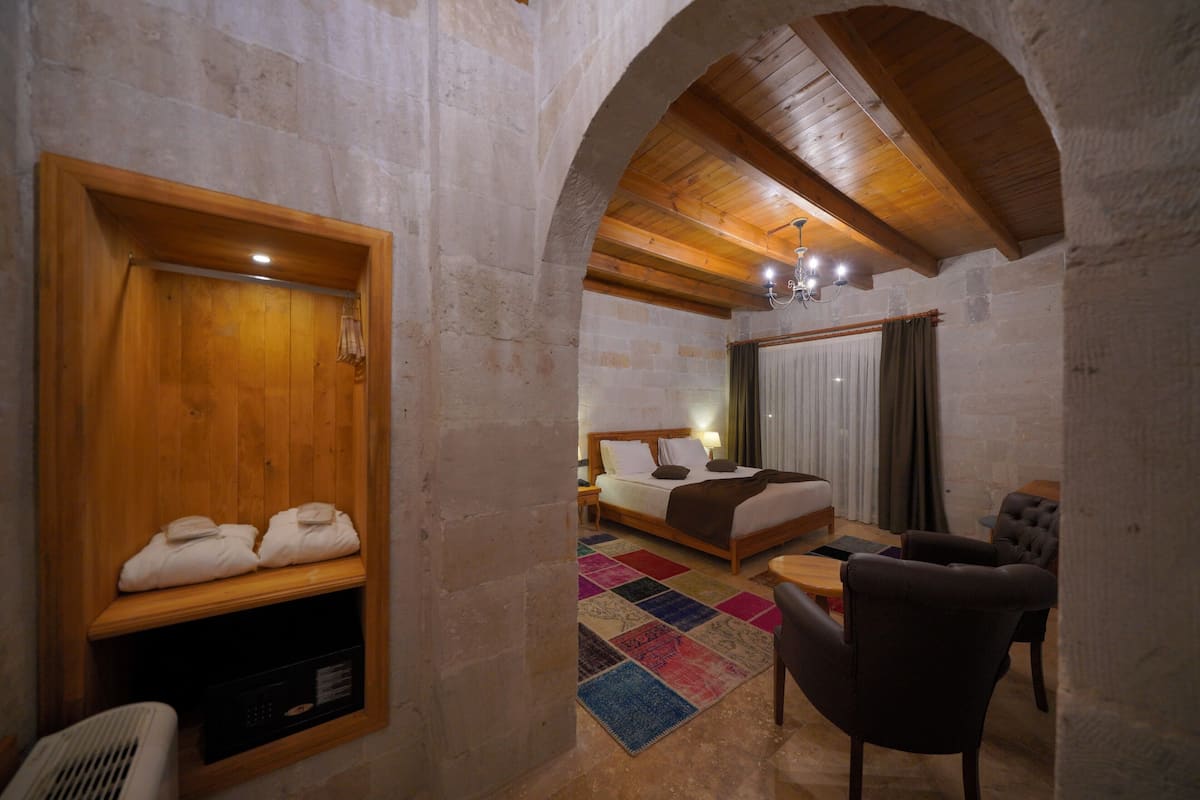 A cozy room with a wooden bench, a bed with pillows, a small table, and a chair.