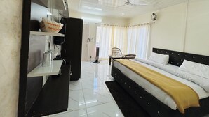 Una habitación de hotel con cama, escritorio, silla, ventilador de techo y ventana con cortinas.