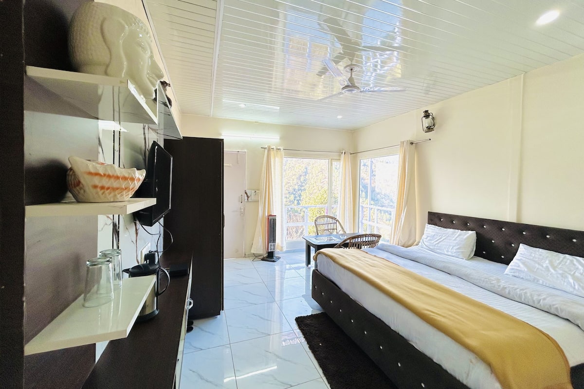 A hotel room with a bed, a TV, a desk, and a view of the outdoors.