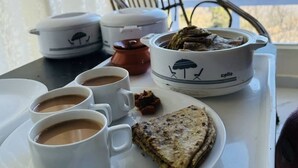 Una bandeja con un plato de comida, dos tazas de café y un bol de sopa.