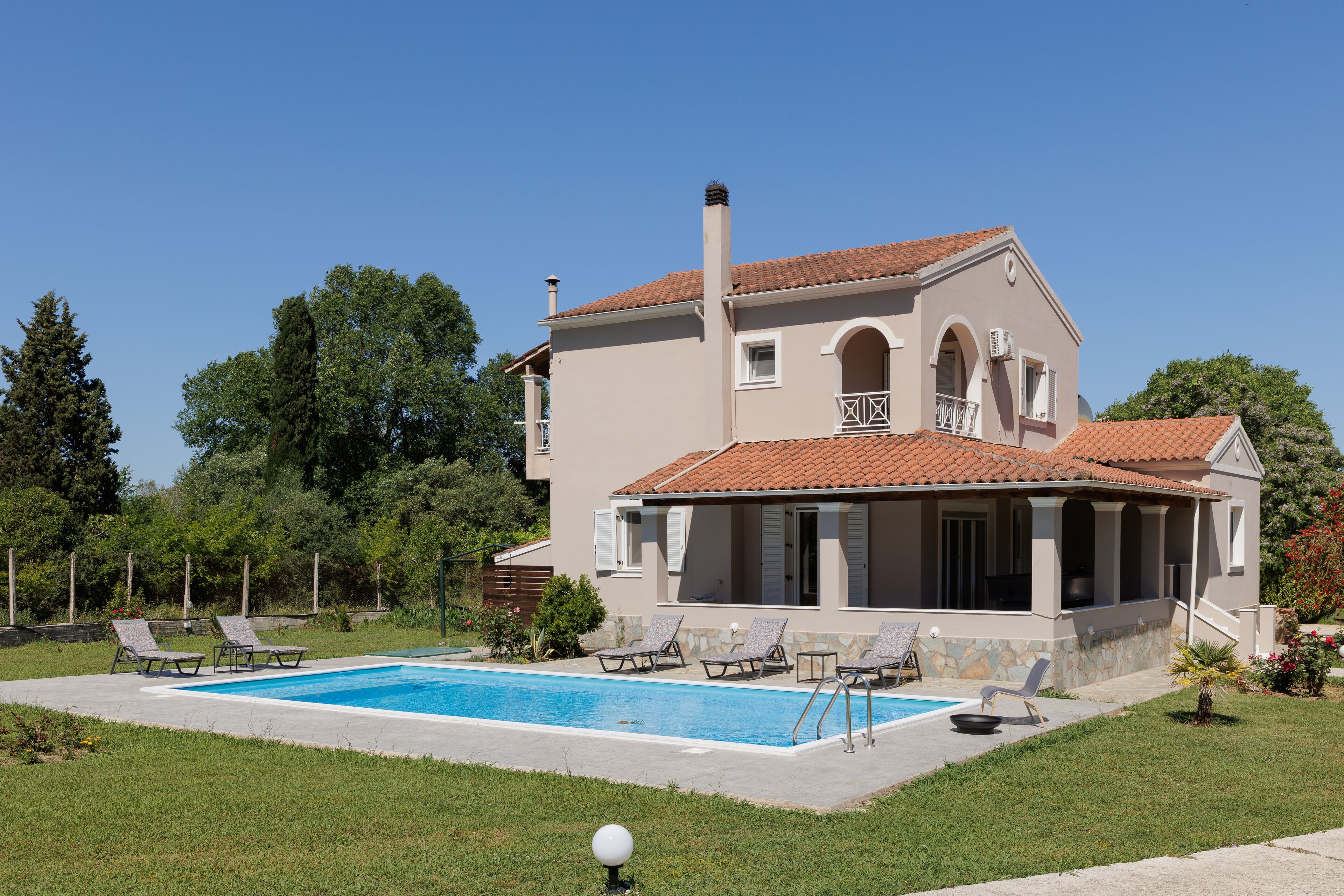 A two-story house with a swimming pool, a covered patio, and a garden.