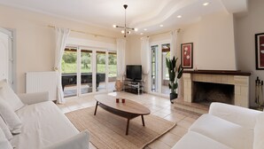 A spacious living room with a large TV, a fireplace, and a comfortable seating area. - Country Villa Verde (Corfu)