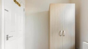 A room with a white door, a wardrobe with two handles, and a radiator on the right. - Abbey House SW London for Big Groups (Colliers Wood)