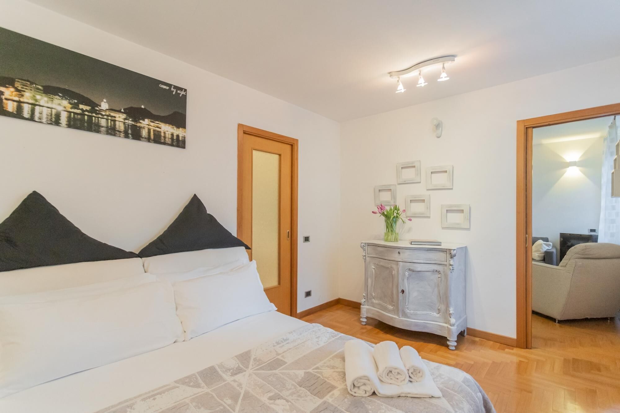 Ein Schlafzimmer mit Bett, Kommode, Spiegel und einem Stadtbild an der Wand.