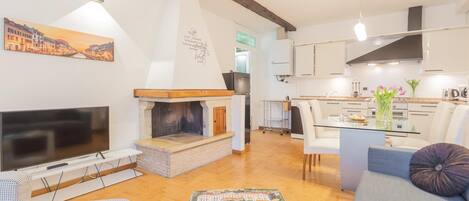 A modern living room with a fireplace, a television, and a dining area with a glass table.