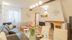 Un salon moderne avec un canapé, une table basse en verre, un vase de fleurs, une cheminée et un téléviseur.