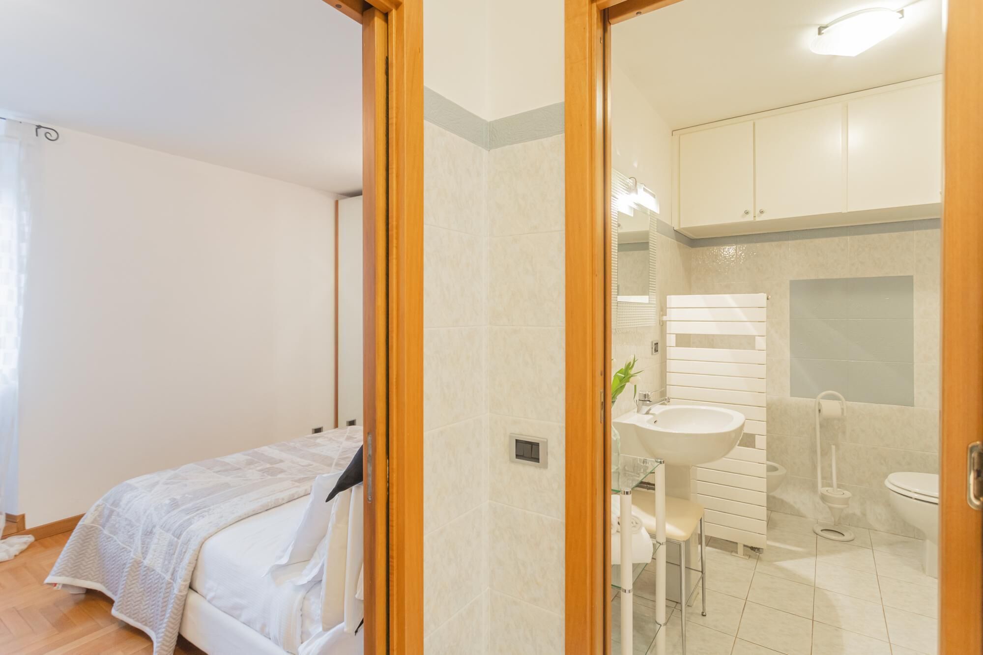 A bedroom with a bed and a bathroom visible through a glass door.