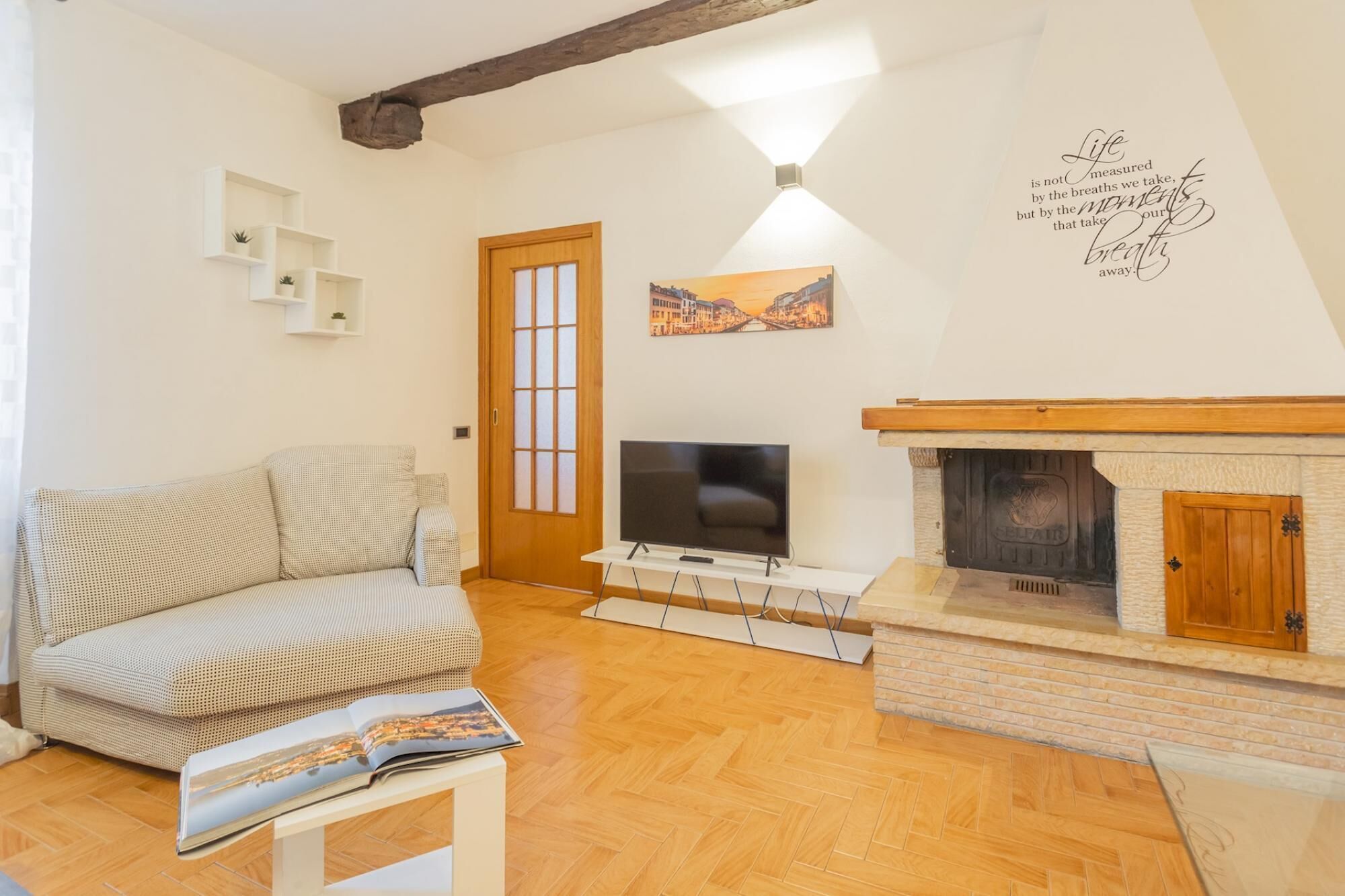 Ein Wohnzimmer mit Sofa, Fernseher, Kamin und einer Wand mit einem Zitat.